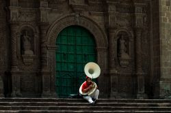 Un musicista seduto sui gradini della cattedrale di Puno suona il sousaphone (tuba) nel pomeriggio, Perù - © Simon Mayer / Shutterstock.com
