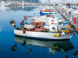 Un pescatore su una piccola barca in legno ormeggiata al porto di Oneglia, Imperia (Liguria) - © Mor65_Mauro Piccardi / Shutterstock.com