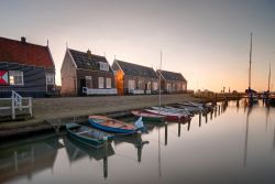 Un pittoresco scorcio del porto di un villaggio sull'isola di Marken, Olanda, al tramonto. Le graziose case in legno e le barche ormeggiate dei pescatori rendono autentica l'atmosfera ...