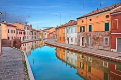 Un pittoresco scorcio del villaggio di Comacchio, provincia di Ferrara, Emilia-Romagna. Le case dalle facciate colorate si riflettono nell'acqua dei canali di questo suggestivo paesino conosciuto ...