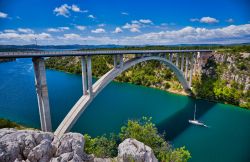 Un suggestivo panorama del ponte Sibenik sul fiume Krka a Skradin, Croazia. Lungo 391 metri, questo ponte in calcestruzzo attraversa il Krka a un'altezza di 65 metri.

