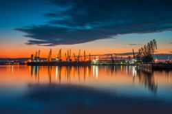 Un suggestivo tramonto colorato sul porto e sulle gru industriali a Varna, Bulgaria.

