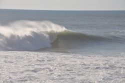 Un surfista impegnato a cavalcare un'onda a Nazaré, Portogallo.
