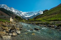 Un torrente nella valle del Circo di Gavarnie, Francia, in estate. Sullo sfondo, le vette dei monti innevate. 

