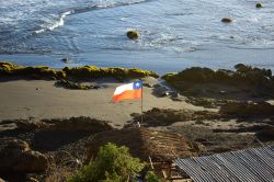 Un tratto del litorale sabbioso di Pichilemu, Cile, con la bandiera che sventola.
