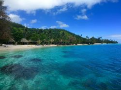 Un tratto di spiaggia sull'isola di Huahine, Polinesia Francese. L'isola è ricoperta da una vegetazione lussureggiante costituita prevalentemente da palme da cocco.

