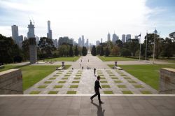 Un uomo cammina al Tempio della Rimembranza di Melbourne, Australia. Sullo sfondo, la skyline della città - © Matt Leane / Shutterstock.com
