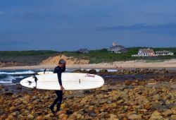 Un uomo con il surf sulla spiaggia di Ditch Plains a Montauk, Oceano Atlantico, New York  - © rj lerich / Shutterstock.com