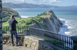 Un uomo fotografa la costa basca da un punto panoramico di Zumaia, Spagna.
