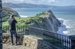 Un uomo fotografa la costa basca da un punto panoramico di Zumaia, Spagna.
