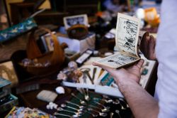 Un uomo sfoglia un libretto comico al mercato delle pulci a Barga, Toscana - © Mykolastock / Shutterstock.com