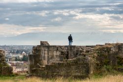 Un uomo sulle rovine dell'antica fortezza di Kutaisi, Georgia, mentre osserva il panorama sulla città - © Tatyana Vyc / Shutterstock.com