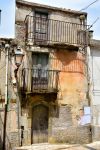 Un vecchio edificio del borgo di Motta Camastra, Sicilia, con i balconi in ferro.

