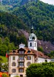 Un vecchio palazzo di Vitznau con dietro chiesa e campanile, Svizzera.

