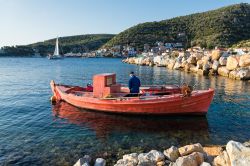 Un vecchio pescatore sulla sua barca in legno a Trikeri, Grecia. La pesca con le tradizionali imbarcazioni rimane un'attività importante per l'economia locale - © dinosmichail ...
