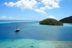 Un veliero ormeggiato al largo dell'isola di Huahine, sud Pacifico, Polinesia Francese. L'acqua assume le tonalità del blu e dell'azzurro.

