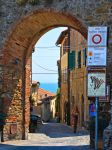 Un vicoletto del centro storico di Castiglione della Pescaia, Toscana. Una delle porte d'ingresso al borgo medievale con il mare sullo sfondo - © poludziber / Shutterstock.com