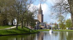 Una barca attraversa un canale di Leeuwarden con il campanile della chiesa, Paesi Bassi.

