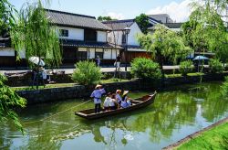Una barca con turisti lungo il canale nella antica città di Kurashiki nei pressi di Okayama, Giappone. Kurashiki è un villaggio storico nella prefettura di Okayama  - © ...