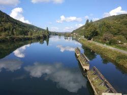 Una barca sul fiume Doubs a Besancon, Francia, in una giornata con il cielo blu e le nuvole.

