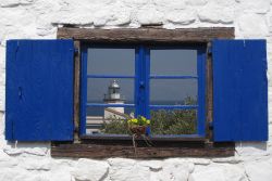 Una bella immagine del faro di Scario che si rispecchia in una finestra del borgo, Campania.



