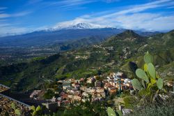 Una bella immagine dell'Etna e di Castelmola, Sicilia. La vetta innevata del complesso vulcanico dell'Etna fa da perfetta cornice all'abitato di Castelmola immerso fra natura e paesaggi ...