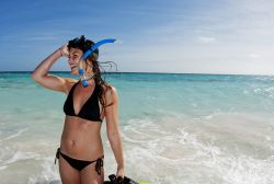 Una bella ragazza sorride su una spiaggia dopo aver fatto snorkeling a Acklins Island, Bahamas. Acklins, che è anche un distretto dell'arcipelago delle Bahamas, si trova in una larga ...