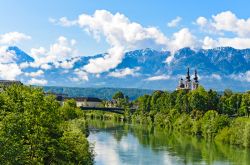 Una bella veduta delle Alpi fotografate da Villach, Austria. Sullo sfondo, una chiesetta sulle rive del fiume.

