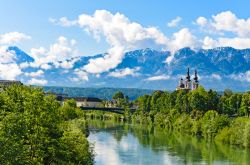 Una bella veduta delle Alpi fotografate da Villach, Austria. Sullo sfondo, una chiesetta sulle rive del fiume.

