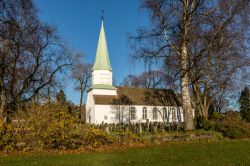 Una chiesa di legno fotografata a Kristiansand in autunno, Norvegia. Immerso nella vegetazione, l'edificio religioso è affiancato da un piccolo cimitero antico.




