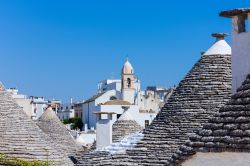 Una chiesa fra i tetti dei trulli di Alberobello, Puglia. Questa cittadina della provincia di Bari è celebre per le costruzioni coniche in pietra presenti a centinaia nel quartiere Rione ...