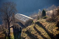 Una chiesa in pietra immersa nel paesaggio agreste vista dall'alto di Triora, Liguria - © Paolo Trovo / Shutterstock.com