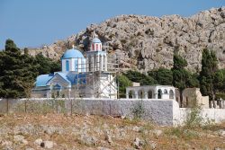 Una chiesetta con la cupola e il tetto azzurro al cimitero di Emborio, isola di Chalki (Grecia). Il campanile è sorretto da un'impalcatura per via di danni strutturali.

