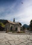 Una chiesetta nel borgo montano di Morzine, Francia. In primo piano, una piazzetta con statua.
