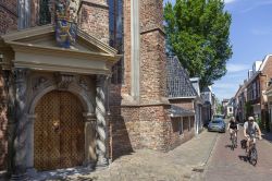 Una coppia a passeggio in bici lungo le strade di Leeuwarden, Paesi Bassi. Sulla sinsitra, il bel portale d'ingresso della chiesa giacobina - © Anton Havelaar / Shutterstock.com