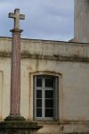 Una croce in pietra su una colonna davanti a una casa a Montpellier, Francia.

