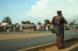 Una donna africana con un abito tradizionale cammina nella città di Conakry (Guinea) nei pressi di un mercato - © Sem Let / Shutterstock.com