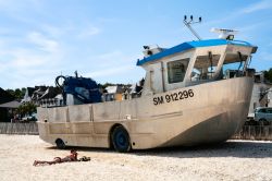 Una donna in relax  sulla spiaggia nei pressi del porto La Houle a Cancale, Francia.  Sullo sfondo, la nave anfibia della città - © vvoe / Shutterstock.com