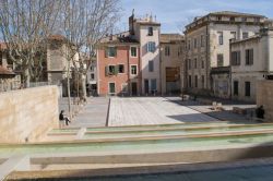 Una donna legge un libro seduta vicino alle fontane in Place du Chapitre a Nimes, Francia - © Travelsewhere / Shutterstock.com