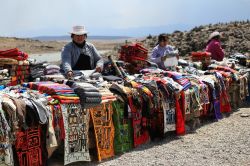 Una donna peruviana vende abiti colorati in alpaca in un tipico mercato per turisti vicino a Arequipa, Perù - © padchas / Shutterstock.com
