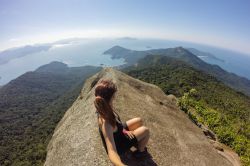 Una donna seduta sulla cima del Pico do Papagaio a Ilha Grande, Rio de Janeiro, Brasile.

