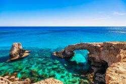 Una donna su uno spettacolare arco di roccia vicino a Ayia Napa, Cape Greco, isola di Cipro. Questo luogo è considerato il ponte degli innamorati.




