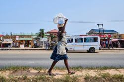 Una donna vende acqua passeggiando lungo una strada della città di Accra, Ghana - © Danilo Marocchi / Shutterstock.com