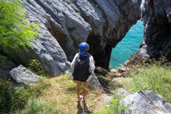 Una giovane donna fa trekking guardando il mare a Phra Nang, Thailandia. Le scogliere chiare si tuffano nel turchese chiaro delle acque cristalline.



