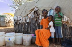 Una giovane donna keniota lava abiti di fronte alla sua casa di Marsabit in compagnia dei figli - © Adriana Mahdalova / Shutterstock.com