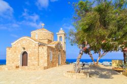 Una graziosa chiesetta in mattoni sulla collina di Protaras, isola di Cipro. A fare da cornice, l'azzurro del cielo e del mare e il verde della vegetazione.

