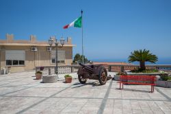 Una piazzetta di Forza d'Agrò, provincia di Messina, con un vecchio cannone e la bandiera italiana che sventola.

