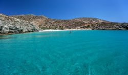 Una piccola spiaggia di sabbia lambita dalle acque dell'Egeo, isola di Donoussa, Grecia. Sullo sfondo una barca ormeggiata.


