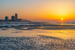 Una pittoresca veduta della spiaggia di Ostenda al tramonto, Belgio: affacciata sul Mare del Nord, questa località è fra le più apprezzate del paese. Sullo sfondo, la skyline ...