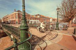 Una signora percorre in bicicletta un ponte a L'Aia, Olanda - © Radiokafka / Shutterstock.com